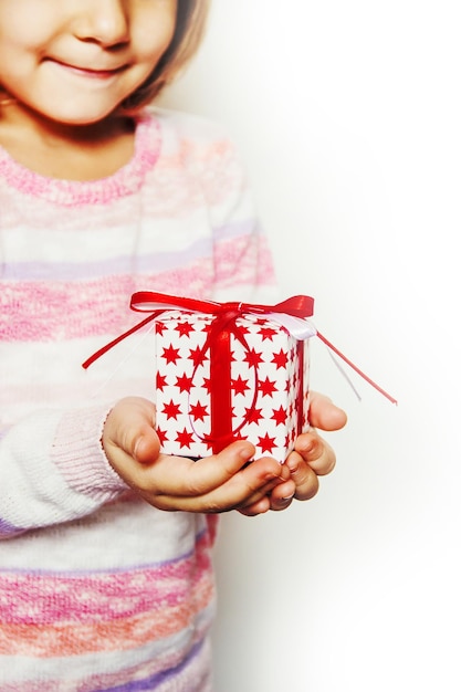 Criança segura uma decoração de Natal e presentes em um fundo branco Foco seletivo