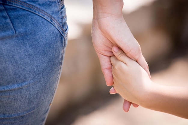 Criança segurando a mão da mãe de um membro da família como uma família unida