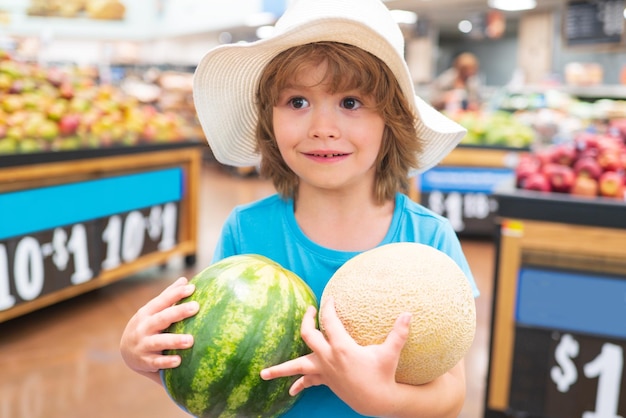 Criança segurando melancia no supermercado Venda consumismo e conceito infantil Legumes na loja