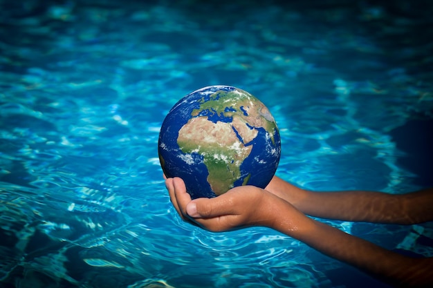 Criança segurando o planeta 3d nas mãos contra o fundo da água azul conceito de feriado do dia da terra elementos desta imagem fornecidos pela nasa