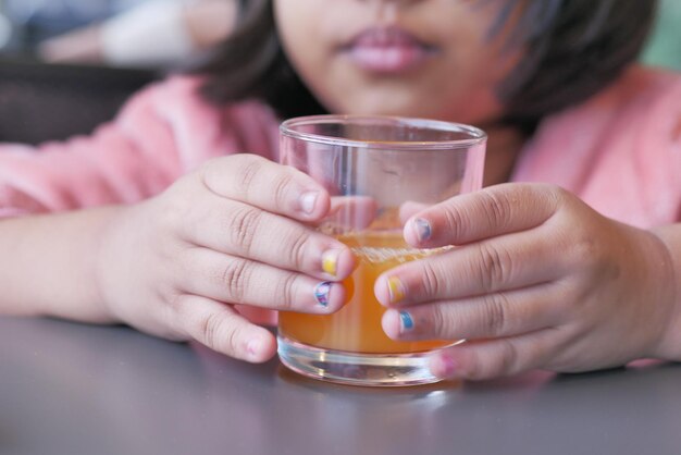 Criança segurando um copo de suco de laranja close-up