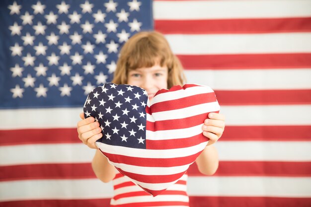 Criança segurando um coração impresso com a bandeira americana 4 de julho, feriado do Dia da Independência