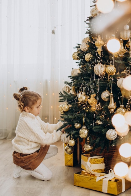 Criança sentada debaixo da árvore de natal