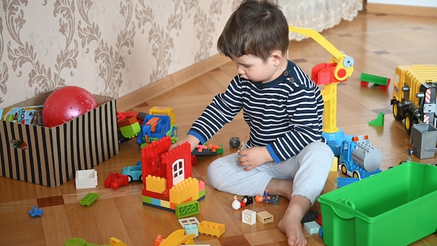 Criança sentada no chão brinca de construtor.