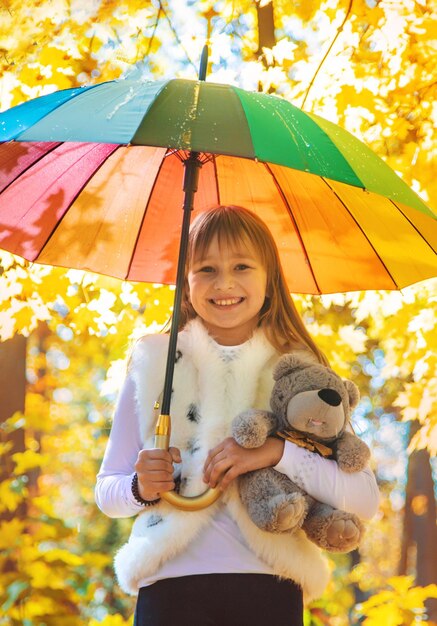 Criança sob um guarda-chuva no parque de outono Foco seletivo