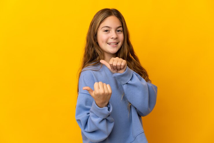 Foto criança sobre fundo amarelo isolado apontando para o lado para apresentar um produto