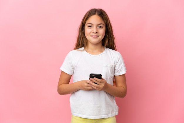 Foto criança sobre rosa isolada olhando para a câmera e sorrindo enquanto usa o celular