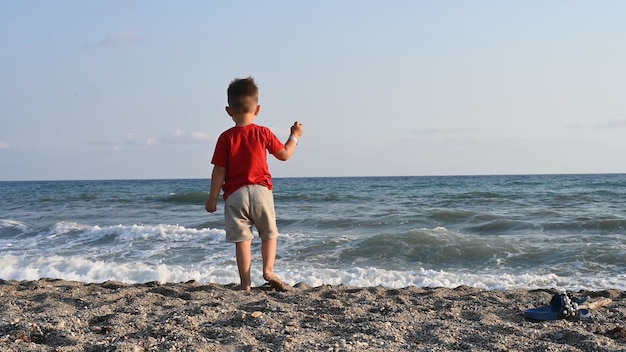 Criança solitária brincando sozinha à beira-mar