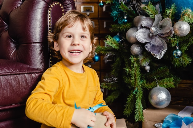 Criança sorridente abrindo presente de Natal