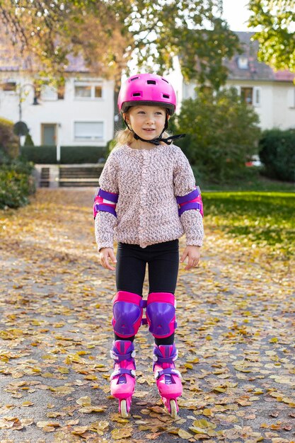 Foto criança sorridente com capacete em patins de proteção no parque