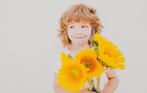 Criança sorridente com girassóis criança feliz com buquê de flores lindo menino adorável romântico e surpresa