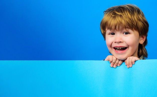 Criança sorridente com tabuleiro vazio garotinho com sinal em branco para banner de publicidade de texto para o seu