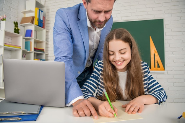 Foto criança sorridente com tutor em sala de aula usa laptop