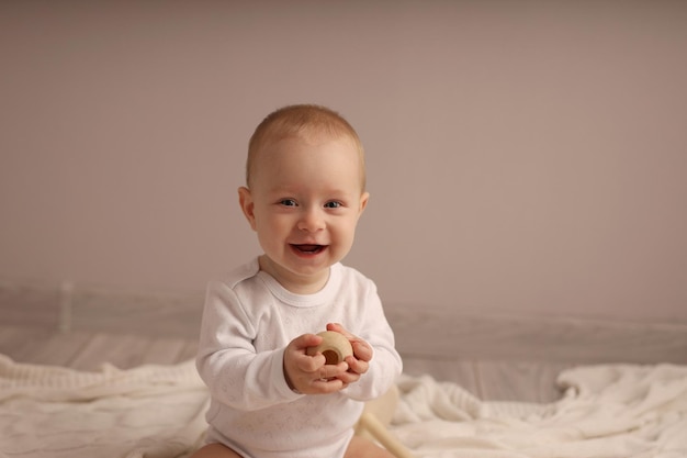 Foto criança sorridente e fofa brincando com uma pirâmide de madeira em uma colcha branca