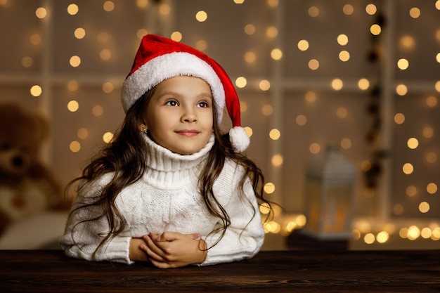 Criança sorridente feliz com chapéu de Papai Noel, sonhando com as férias