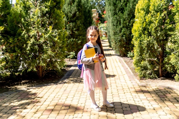 Criança sorridente feliz indo para a escola pela primeira vez menina com bolsa vai para a escola primária