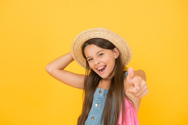 Criança sorridente no chapéu de palha criança pronta para atividade de praia feliz infância alegre férias de verão e férias criança moda sazonal beleza despreocupada em fundo amarelo