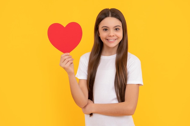 Criança sorridente segura amor na venda de dia dos namorados de fundo amarelo