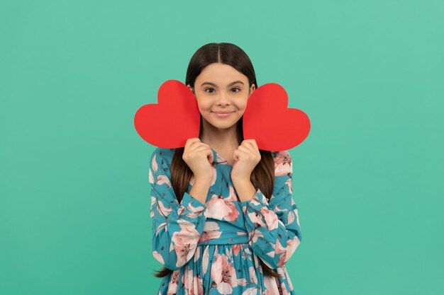 Criança sorridente segura símbolo de coração vermelho de amor pelo amor do dia dos namorados