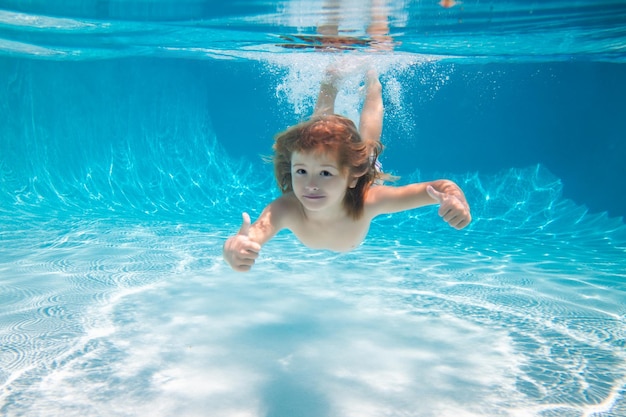 Criança subaquática na piscina criança nadar e mergulhar criança subaquática com polegar para cima na piscina ativa ...