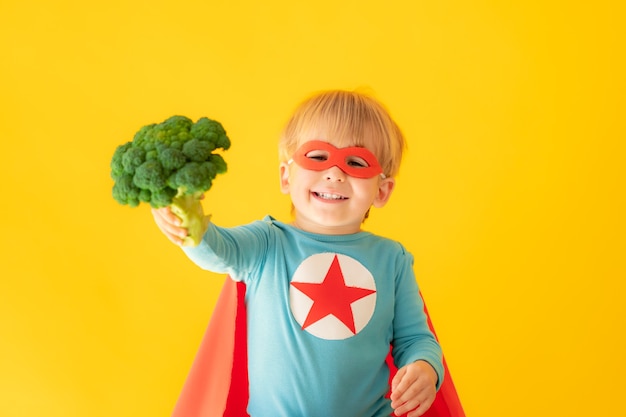 Criança super-herói segurando brócolis