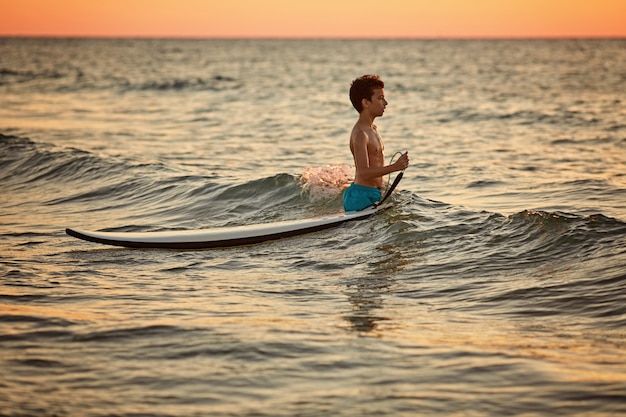 Criança surfando na praia tropical