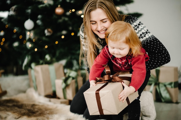 Criança surpreendendo sua mãe com um presente de Natal Família aberta caixa de presentes Feliz Natal e Boas Festas Feliz Ano Novo 2021