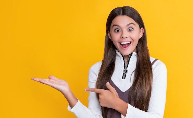 Criança surpreendida com cabelo comprido em fundo amarelo apresentando produto