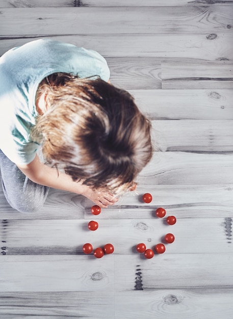 Criança, tocando, com, tomates cereja, ligado, um, luz, chão madeira, de cima