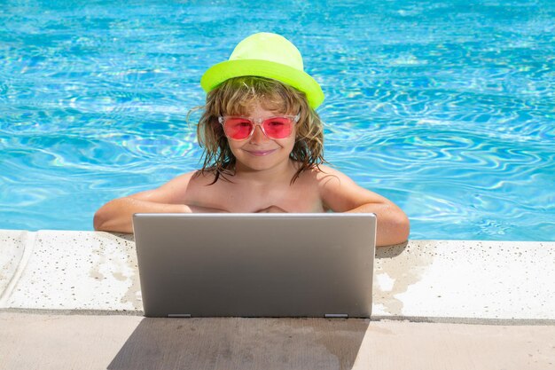 Criança trabalhando no computador portátil na piscina Tecnologia online de verão Viajante relaxando na água tropical nas férias de férias de verão Viagem criança usando laptop