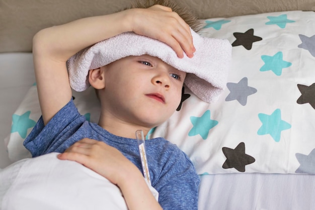 Criança triste doente com temperatura e dor de cabeça deitada na cama Vírus da doença dos resfriados da gripe