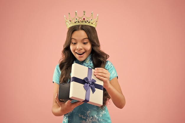 Criança usa coroa dourada símbolo da glória Concurso de beleza Pequena princesa Menina usa coroa Maneiras de princesa Conceito de prêmio Caixa de presente Vencedor do concurso de beleza Concurso internacional de beleza