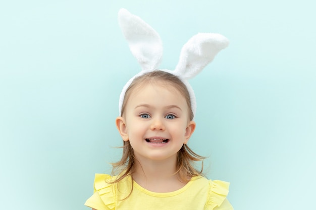 criança usando uma faixa de orelhas de coelho e um vestido amarelo azul
