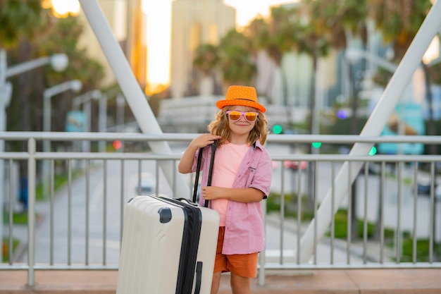 Criança viajante segurando mala turista ao ar livre garoto garoto tendo uma alegre viagem de férias