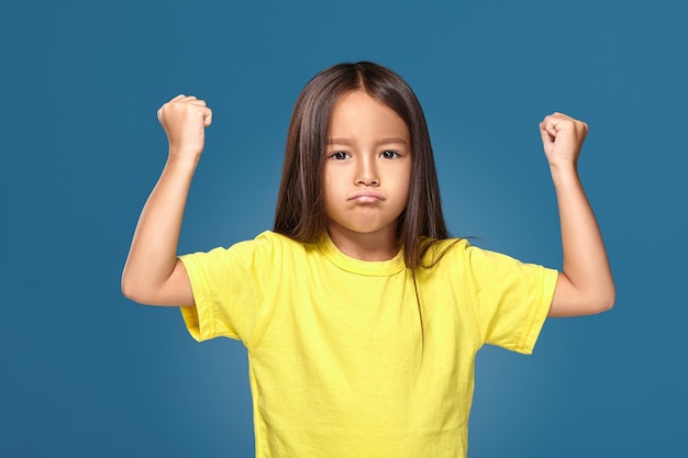 Foto criança zangada mostrando frustração e desacordo sobre fundo azul