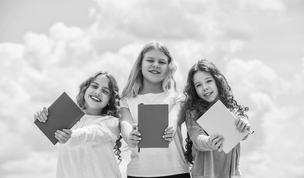 crianças a ler livros três raparigas a escrever num caderno de notas de volta à escola a escrever memórias num diário Educação e conceito escolar Alunos a aprender literatura Perdidos num conto de fadas