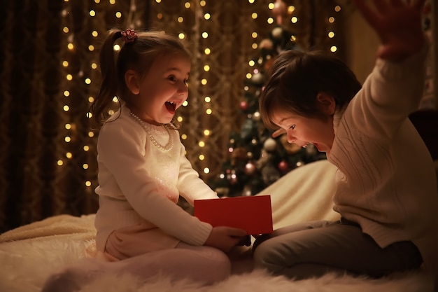 Crianças abrindo natal presentes crianças sob a árvore de natal com caixas de presente