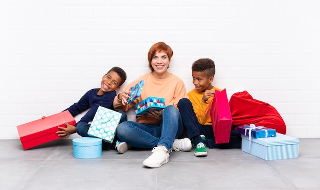 Crianças afro-americanas com sua mãe entre muitos presentes para as férias de natal