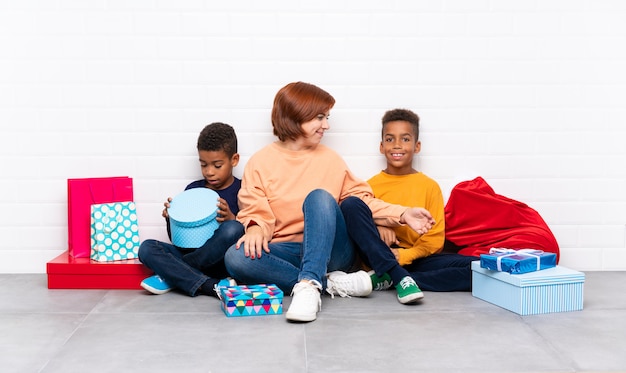 Crianças afro-americanas com sua mãe entre muitos presentes para as férias de Natal