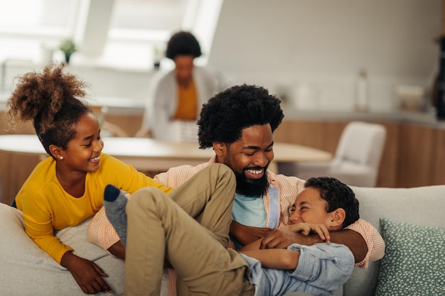 Crianças afro se divertem com o pai no aconchego da sala de estar