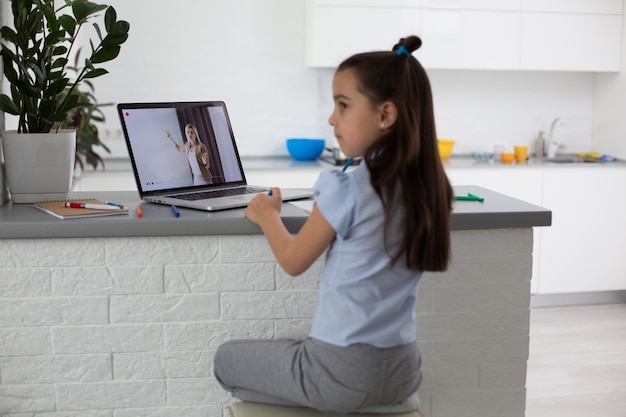 Foto crianças alegremente fofas animadas usando trabalhos escolares de aprendizagem de computador. criança gosta de e-learning nas férias em casa.