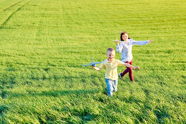 Crianças alegres e felizes brincam no campo e se imaginam pilotos em um dia ensolarado de verão Crianças sonham em voar e aviação