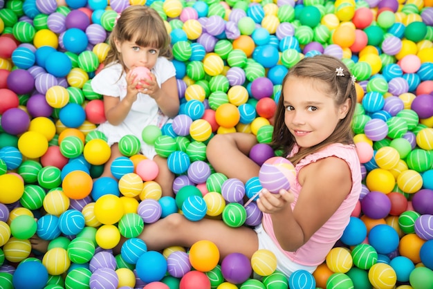 Crianças alegres na sala de jogos com bolas de plástico
