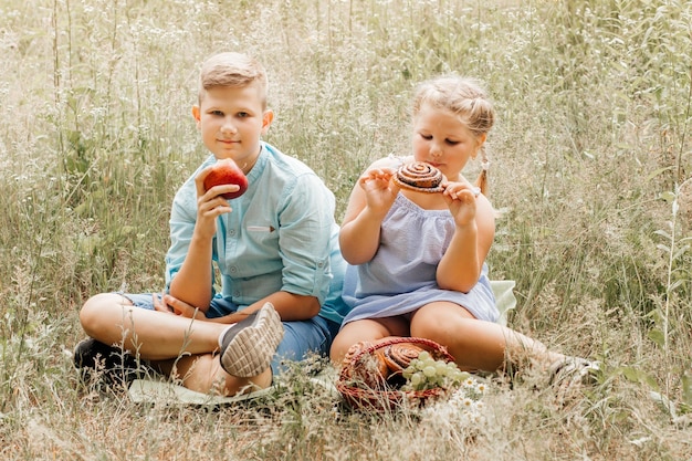 Crianças almoçando ao ar livre Crianças no piquenique no jardim da primavera Menina pré-escolar e menino skool comem e bebem no parque de verão