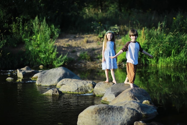 Crianças andam no verão na natureza criança em uma manhã ensolarada de primavera no parque viajando com crianças