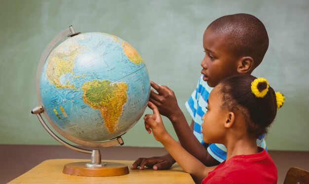 Crianças apontando para o globo na sala de aula