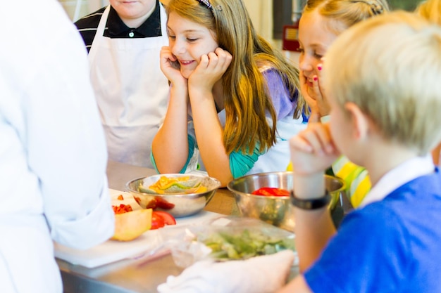 Crianças aprendendo a cozinhar em uma aula de culinária.