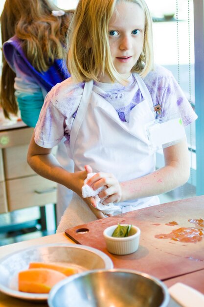 Crianças aprendendo a cozinhar em uma aula de culinária.