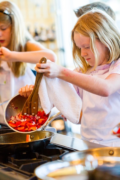 Crianças aprendendo a cozinhar em uma aula de culinária.