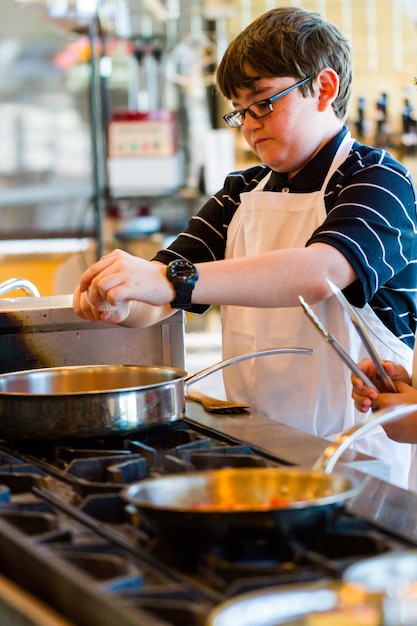 Crianças aprendendo a cozinhar em uma aula de culinária.